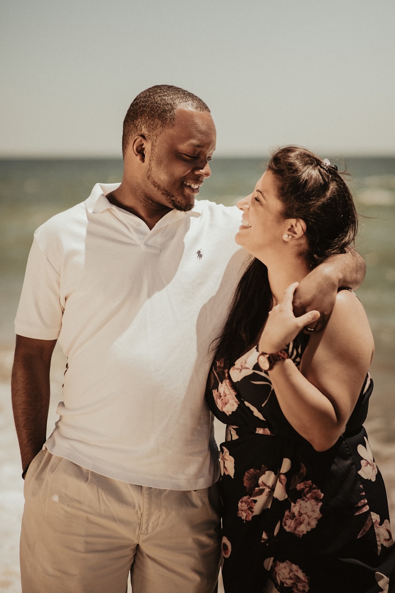 man in white polo shirt kissing woman in black and pink floral dress