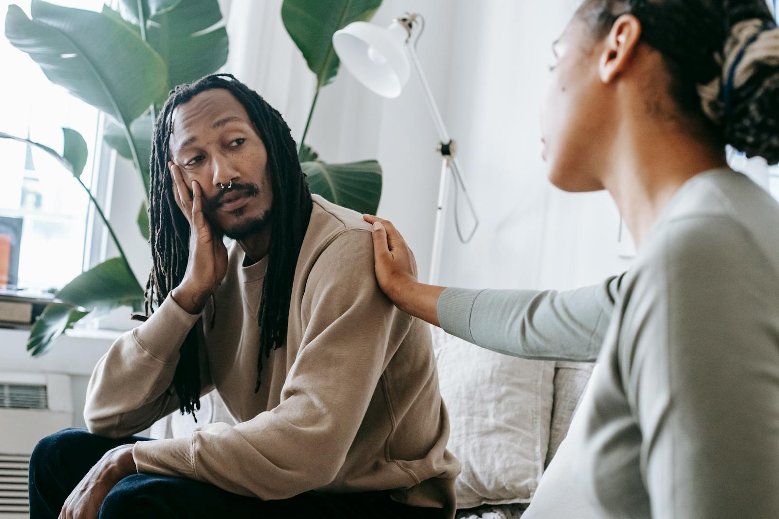 Two diverse individuals having an empathetic conversation in a cozy indoor setting.