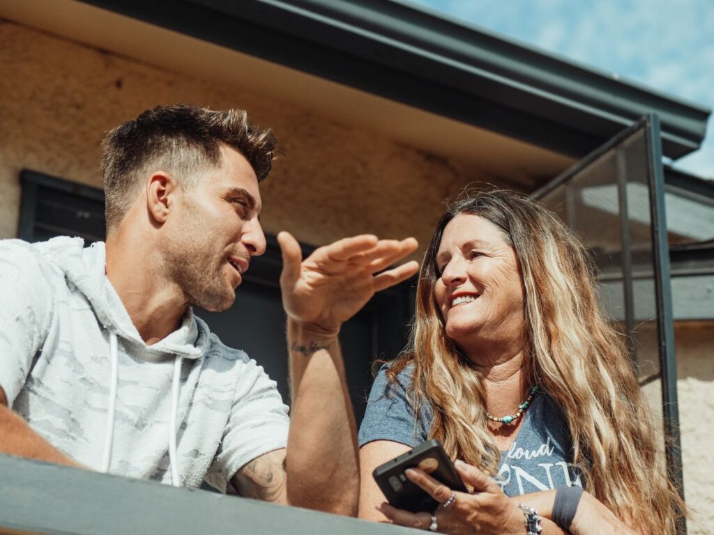 A mother and son enjoying a lively conversation on a sunny outdoor balcony.