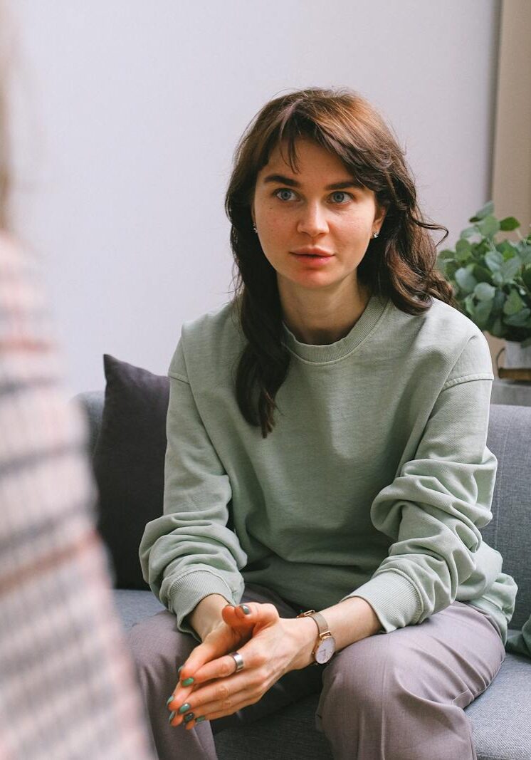 A focused woman during a therapy session, seated on a sofa indoors.
